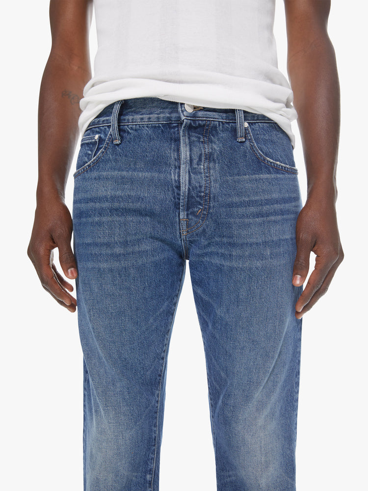 Front detail view of a men's medium blue straight leg jean