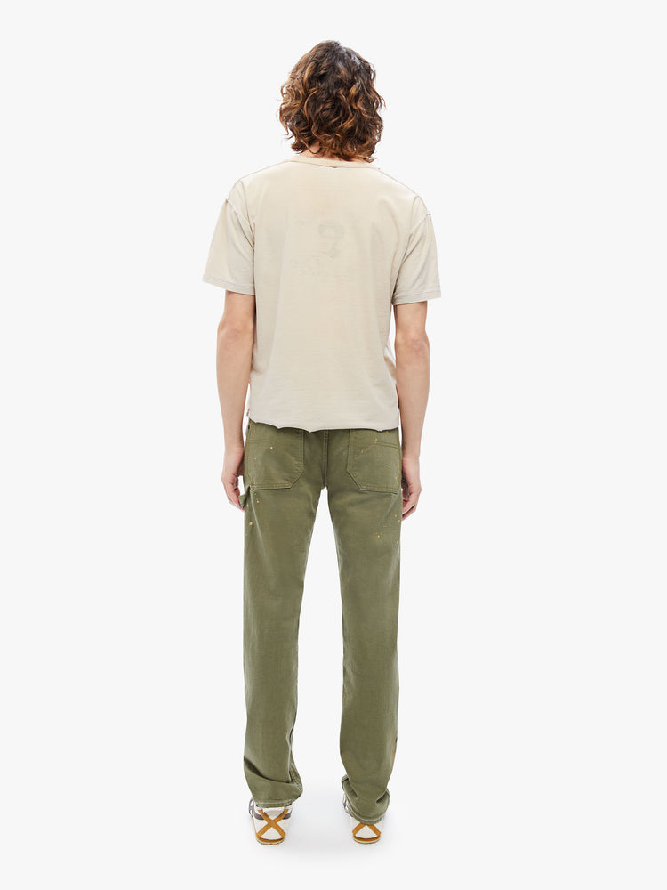 Back view of a mens classic pant with utilitarian pockets, a hammer loop and relaxed leg in an army green hue with paint splatters and tonal hardware.