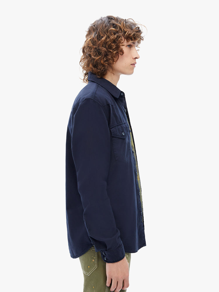 Side view of a mens classic Western-inspired shirt with snap buttons, flap patch pockets, long sleeves and a curved hem in a deep navy hue with tonal hardware.