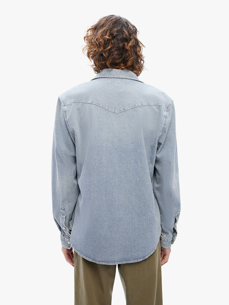 Back view of a mens classic Western-inspired shirt with snap buttons, flap patch pockets, long sleeves and a curved hem in a light-blue wash with navy pinstripes.