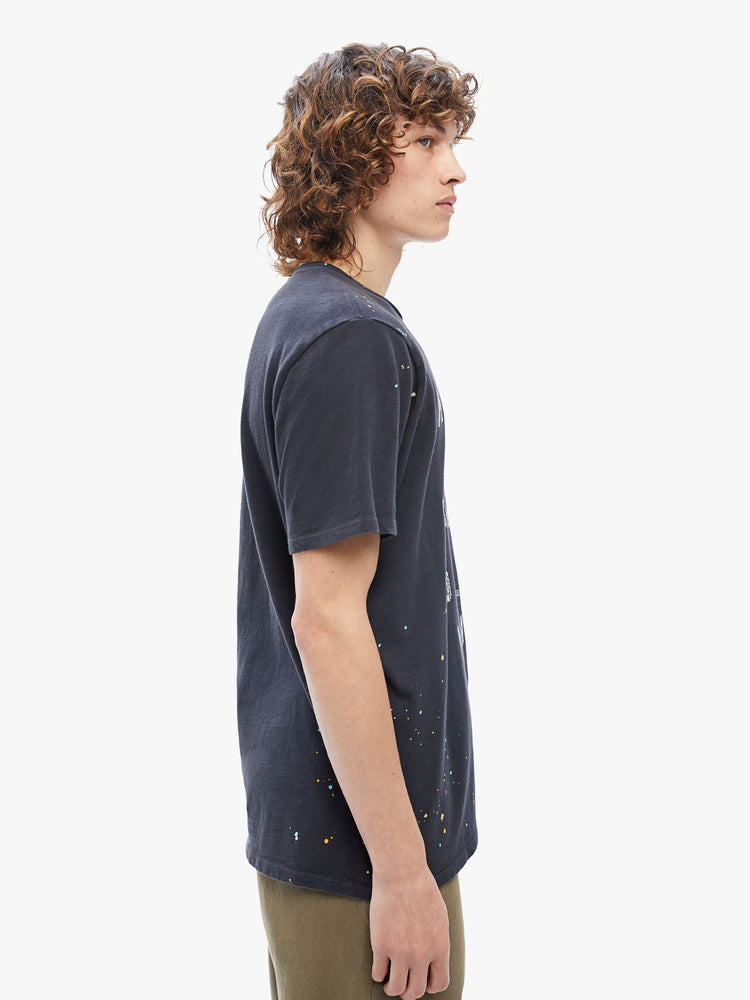 Side view of a mens classic crewneck tee with short sleeves and a boxy fit in black, the tee features faded white text on the front.