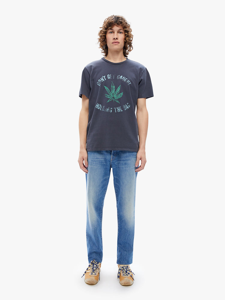 Full body view of a mens classic crewneck tee with short sleeves and a boxy fit, n black, the tee features a faded weed leaf graphic and some advice from MOTHER on the front.