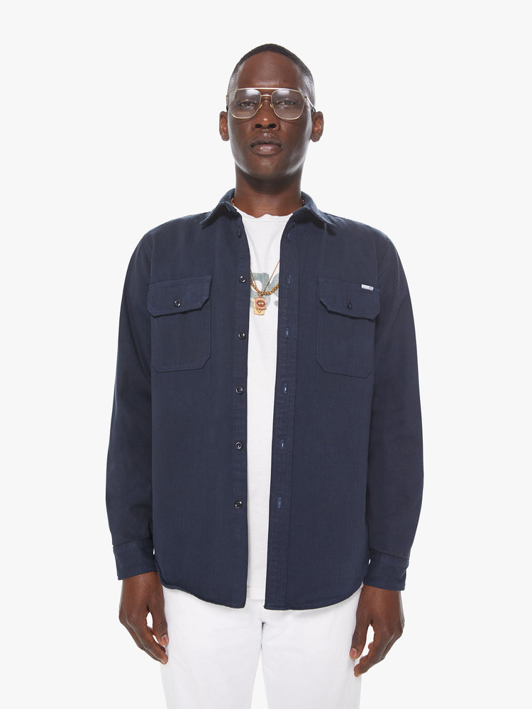 Front view of a men's dark blue shirt with snap buttons and front patch pockets with buttoned pocket flaps