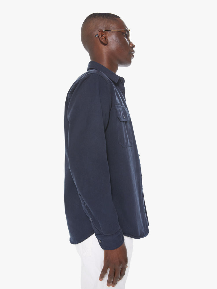 Side view of a men's dark blue shirt with snap buttons and front patch pockets with buttoned pocket flaps