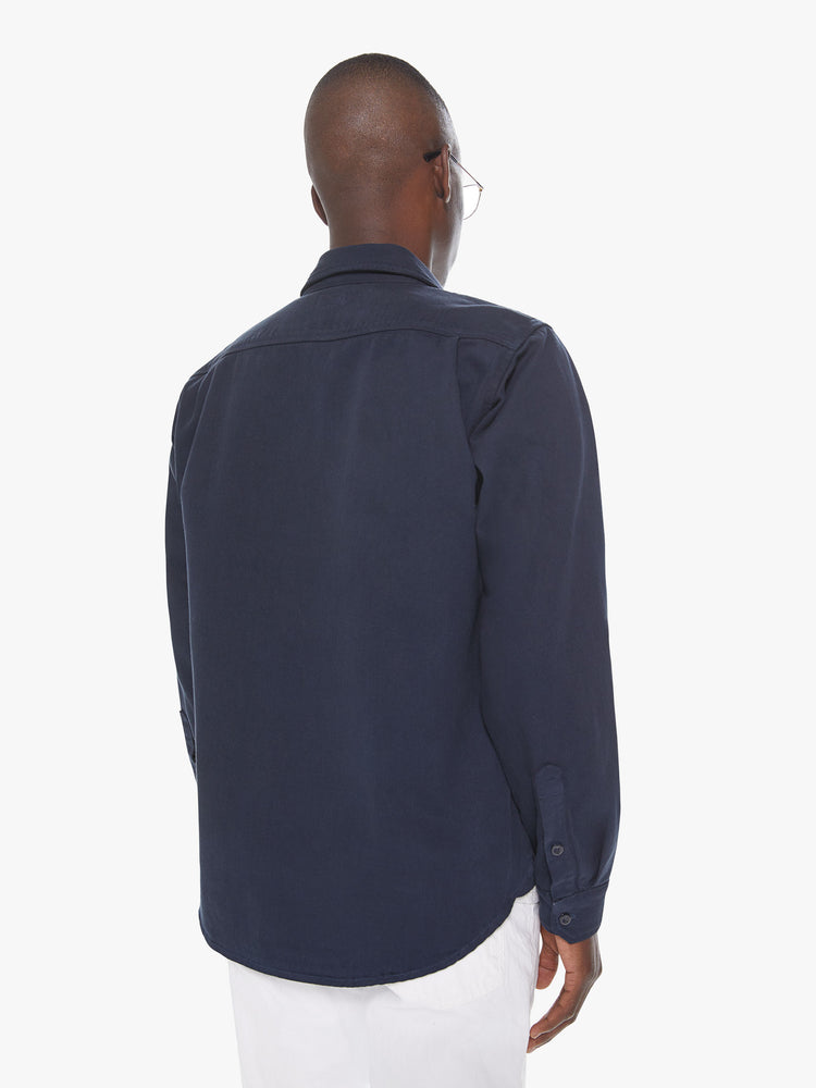 Back view of a men's dark blue shirt with snap buttons and front patch pockets with buttoned pocket flaps
