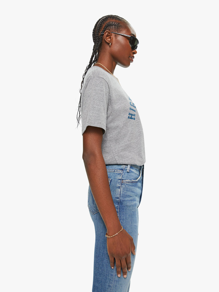 WOMEN side view of a woman in a heather grey unisex crew neck tee featuring a faded blue graphic of hands of the words "HIGHER HOPES".