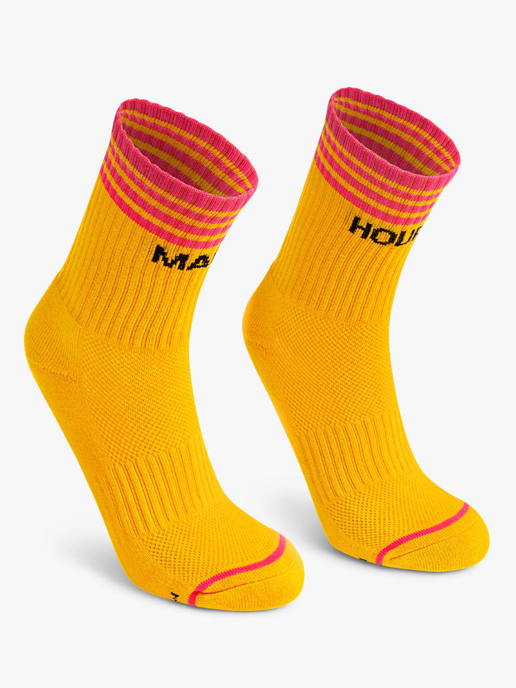 View of a pair of deep yellow socks with dark pink stripes and the words "MAGIC" and "HOUR".