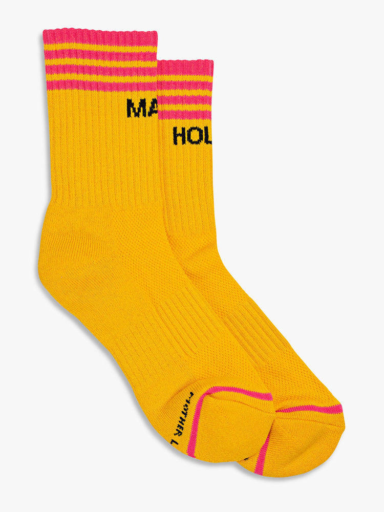Flat view of a pair of deep yellow socks with dark pink stripes and the words "MAGIC" and "HOUR".