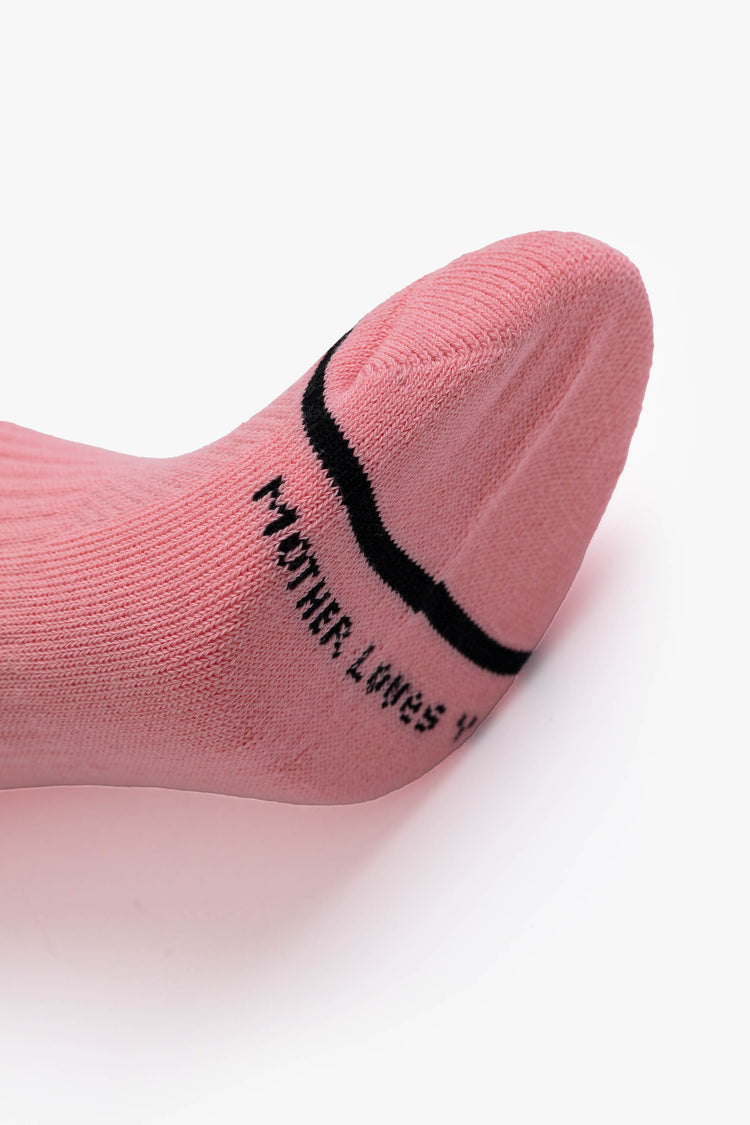 Toe detail view of a light pink women's ankle tube sock featuring "MOTHER FUCKER" in black across the front with a black toe stripe and "MOTHER LOVES YOU" spanning below the toe bed