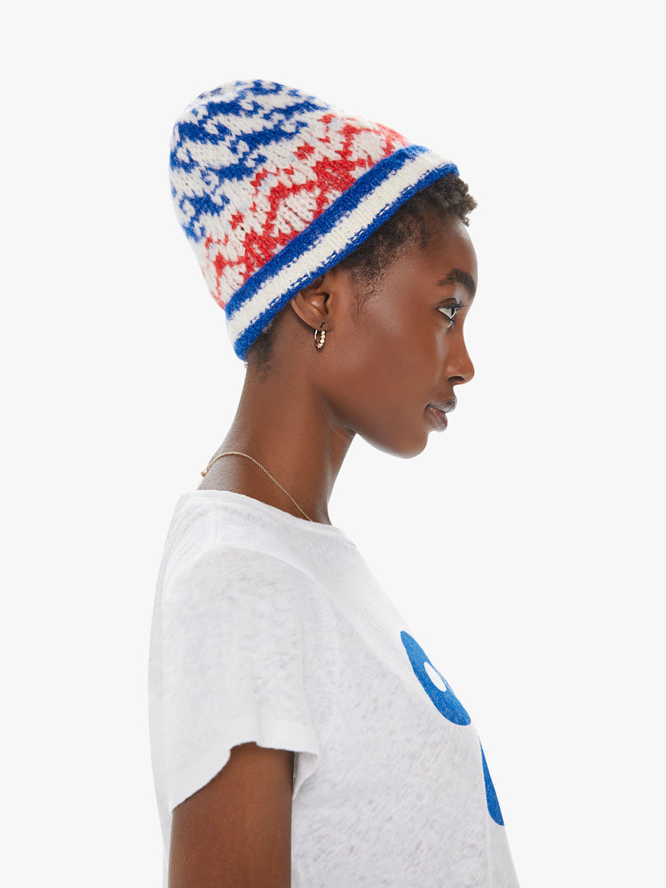 Profile view of a woman wearing an off white knit beanie featuring a festive red and blue pattern.