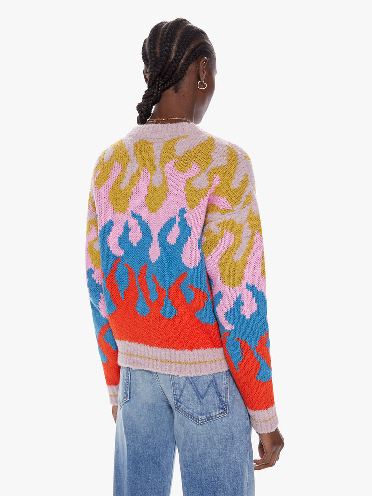 Back view of a womens slightly cropped with long roomy sleeves crewneck sweater with a colorful flame design and stripes at the hem