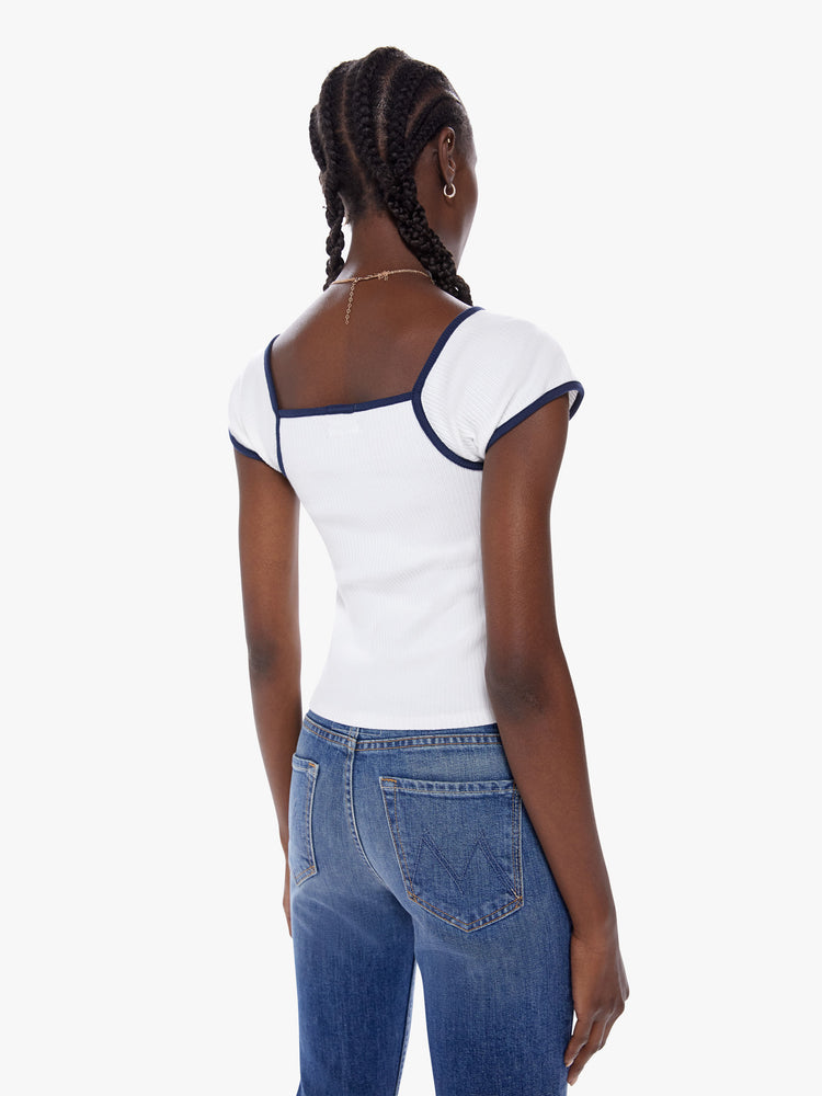 Back view of a woman in a fitted knit top with a square neck, cap sleeves and a cropped hem made from a stretchy ribbed cotton, in a clean white hue with a navy blue trip for a 90s vibe