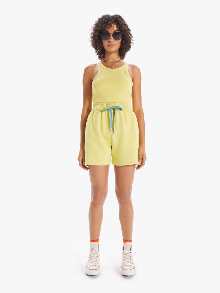 Front full body view of a woman wearing a light yellow tank top.