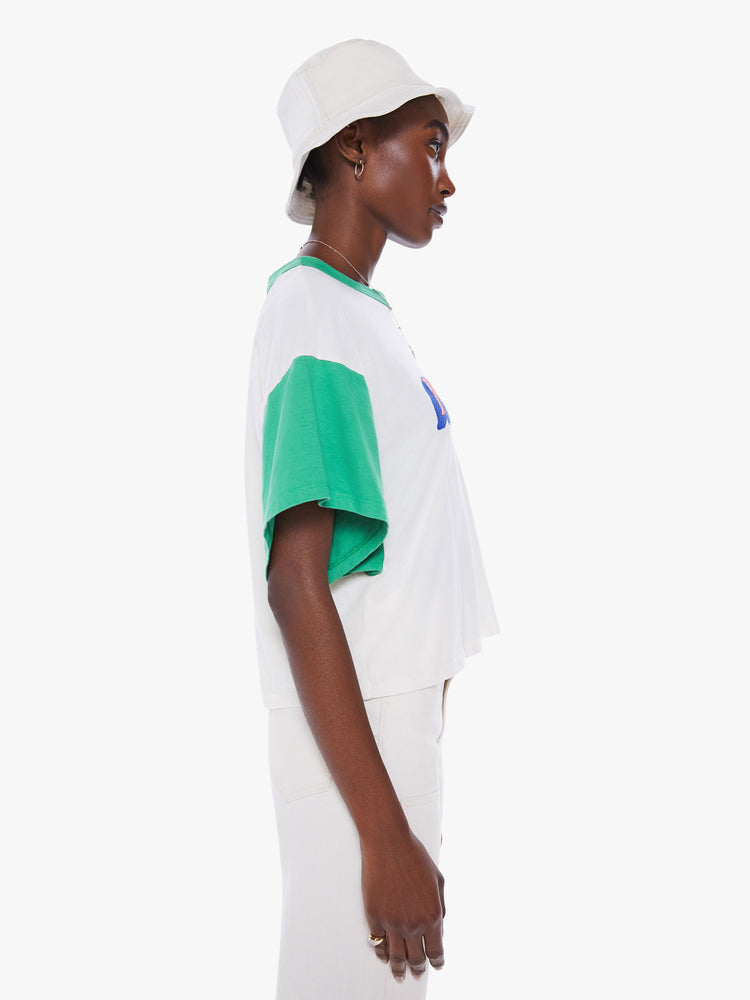 Side view of woman oversized cropped tee with drop shoulders, subtle bat wings and a boxy fit in white with teal crewneck and sleeves with graphic in 3D text.