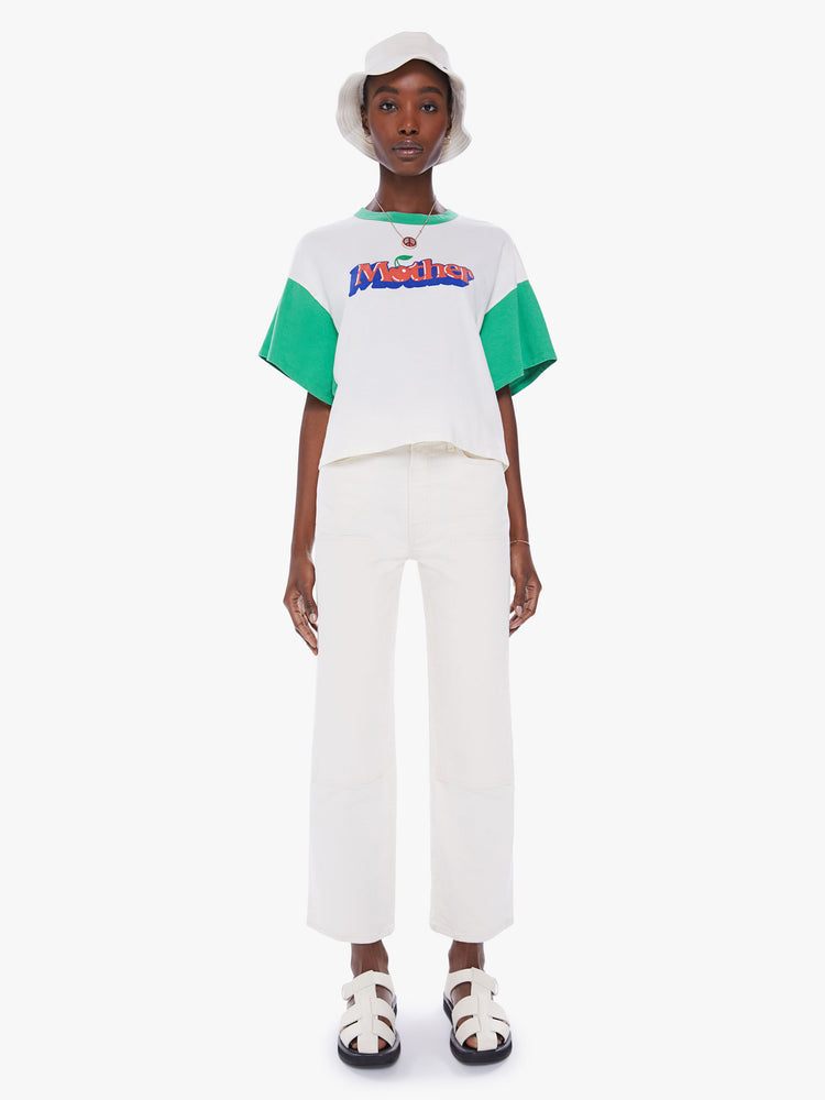 Full body view of woman oversized cropped tee with drop shoulders, subtle bat wings and a boxy fit in white with teal crewneck and sleeves with graphic in 3D text.