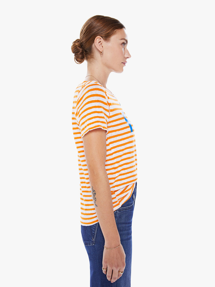 Side view of a woman's boxy crewneck with short sleeves and a cropped hem in orange stripes and bright blue text.