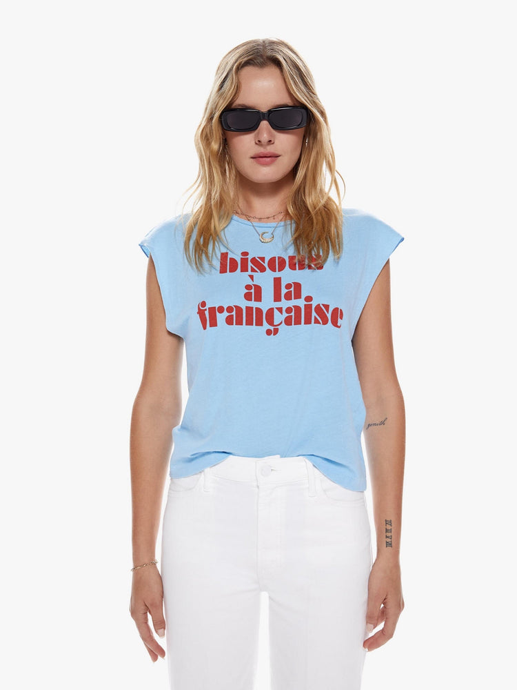 Front view of a woman in crewneck tee with raw cutoff sleeves and a clean hem cut from a blend of recycled cotton in a sky blue hue featuring with a red text graphic in French on the front