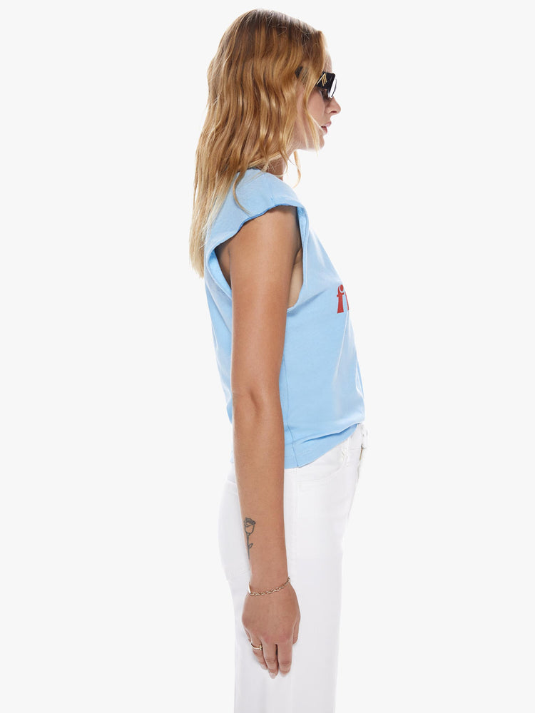 Side view of a woman in crewneck tee with raw cutoff sleeves and a clean hem cut from a blend of recycled cotton in a sky blue hue featuring with a red text graphic in French on the front