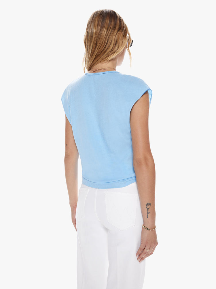 Back view of a woman in crewneck tee with raw cutoff sleeves and a clean hem cut from a blend of recycled cotton in a sky blue hue featuring with a red text graphic in French on the front