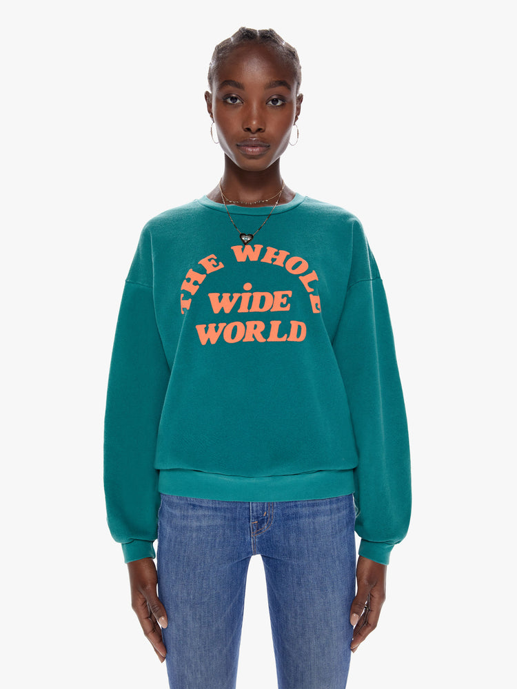 Front view of a woman in a crewneck sweatshirt with dropped sleeves, a relaxed fit in a dark turquoise hue that features puff-ink text that reads The Whole Wide World