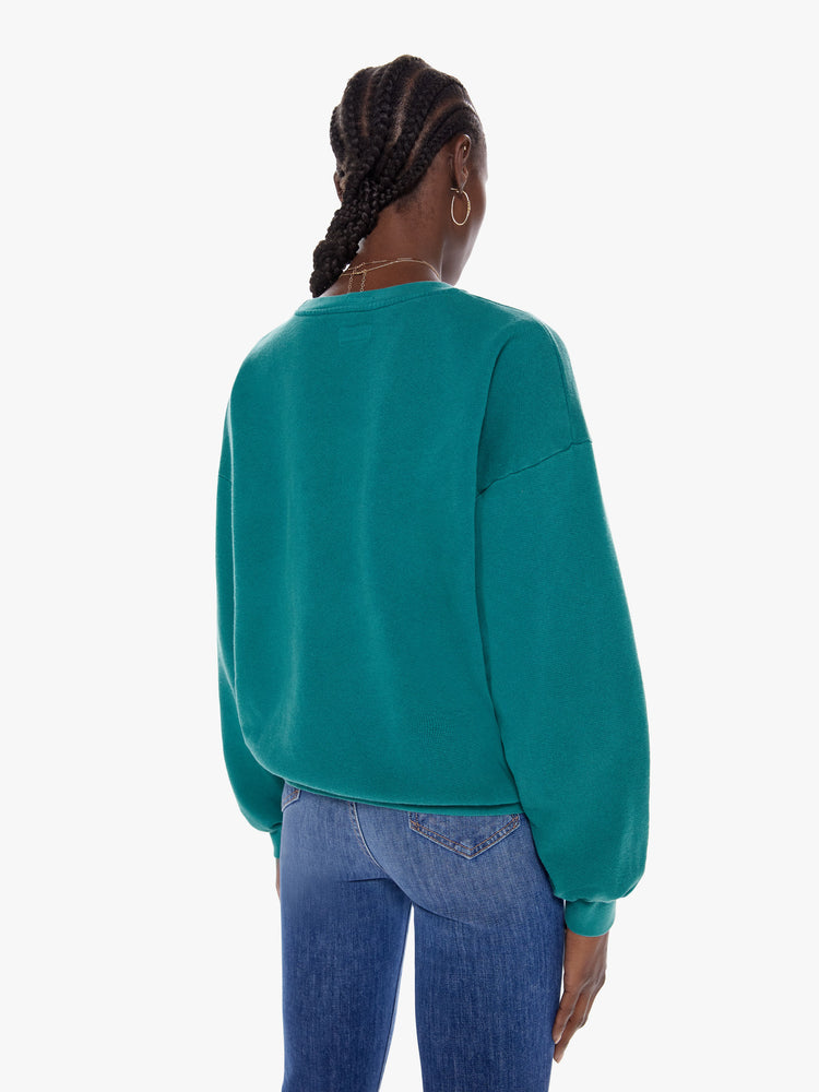 Back view of a woman in a crewneck sweatshirt with dropped sleeves, a relaxed fit in a dark turquoise hue that features puff-ink text that reads The Whole Wide World