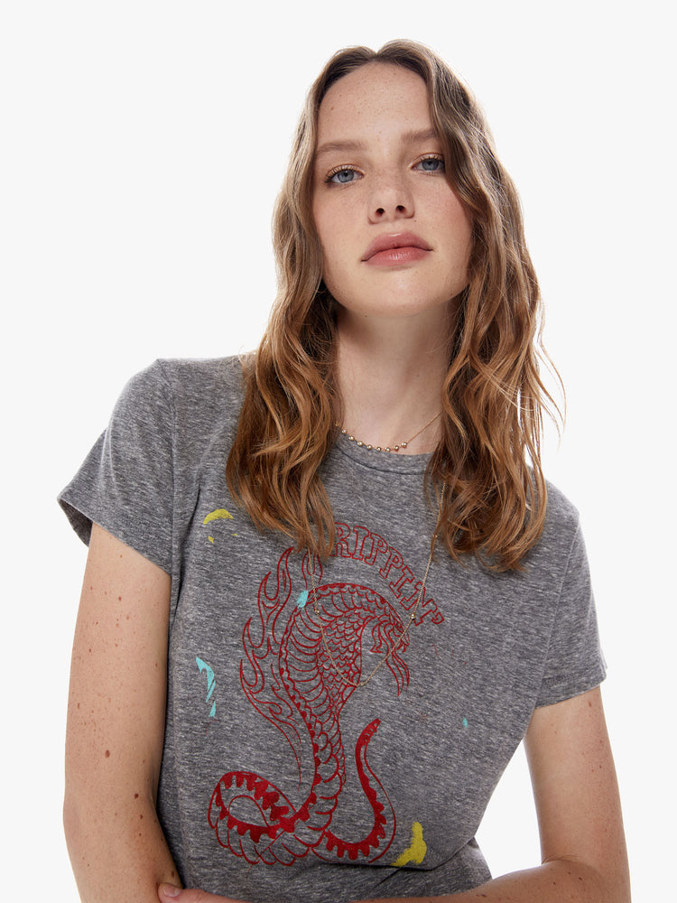 Close up view of a woman in a soft crewneck with a slim fit for a vintage look and feel made from a cotton blend in a heathered grey hue, the tee features a faded cobra snake graphic in red and paint smears on the front