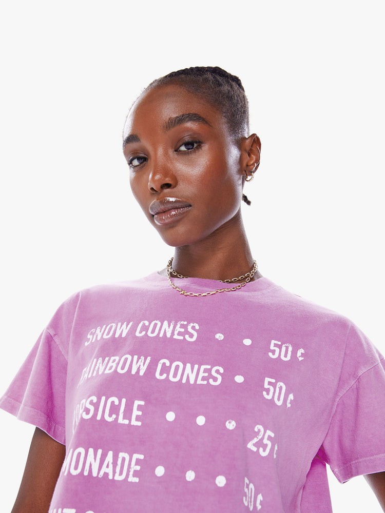 Close up view of woman's cropped tee with a ribbed crewneck, drop shoulders and a boxy fit in a a washed fuchsia hue with white text.