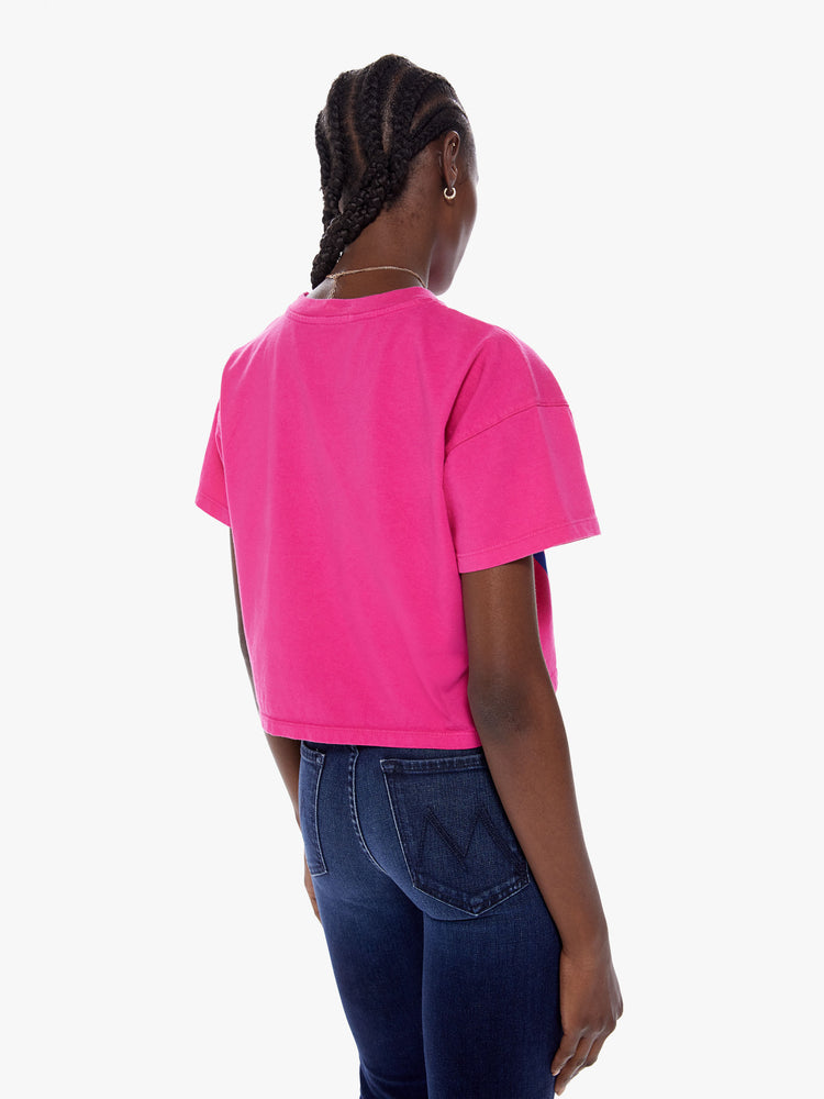 Back view of woman cropped tee with a ribbed crew neck, drop shoulders and a boxy fit in a bright fuchsia hue with blue text on the front.