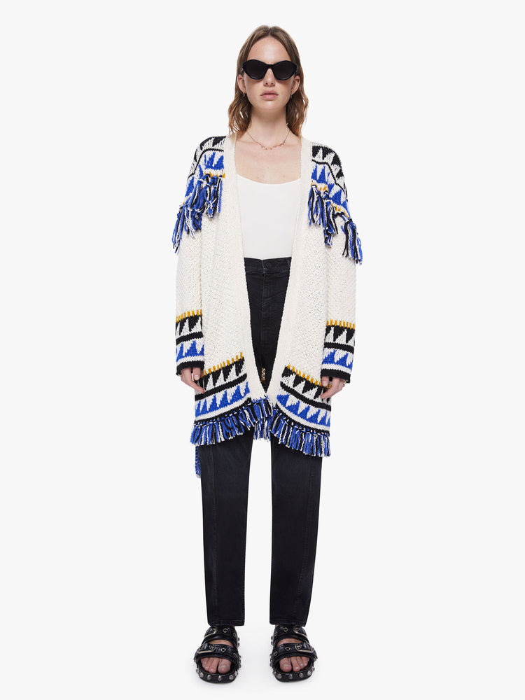 Front view of a womens black and blue triangle print thigh length cardigan sweater with orange knit details, tassels across the chest, arms, hems and a slight dropped shoulders and a boxy oversized fit