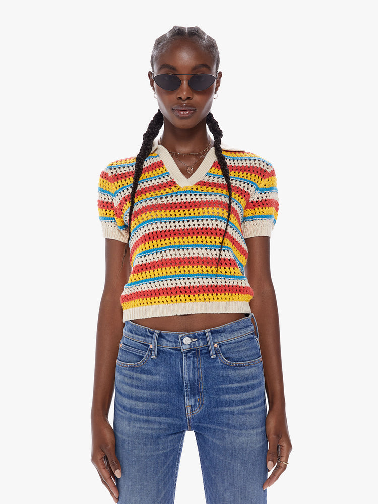Front view of a woman in a collared vneck blouse with short, slightly puffed sleeves and a cropped hem made from 100% cotton in bright orange, yellow and blue horizontal stripes, the knit top features a crochet style design with all over eyelets for a lightweight feel