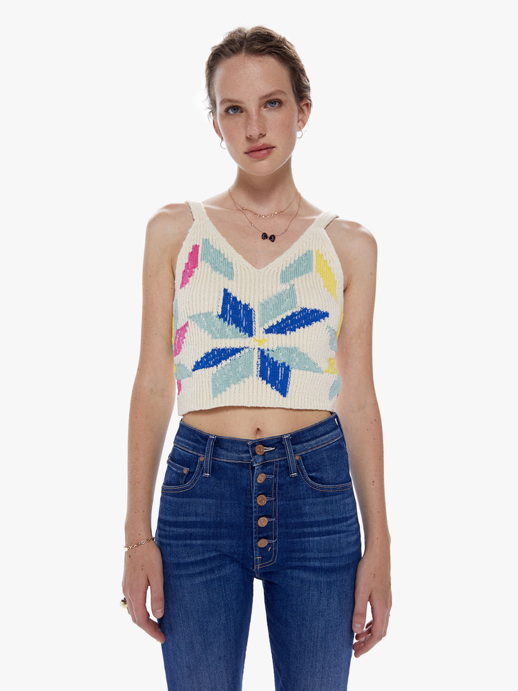Front view of a woman  knit top with a V-neck, thick straps and a cropped fit designed in an off-white hue with a colorful pinwheel motif on the front.