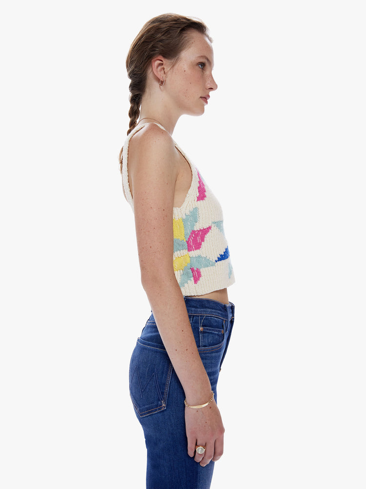 Side view of a woman knit top with a V-neck, thick straps and a cropped fit designed in an off-white hue with a colorful pinwheel motif on the front.