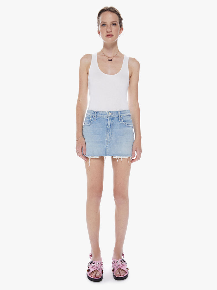 Front view of a woman  denim mini skirt with a mid rise, frayed hem and exposed pocket lining in a light blue wash.