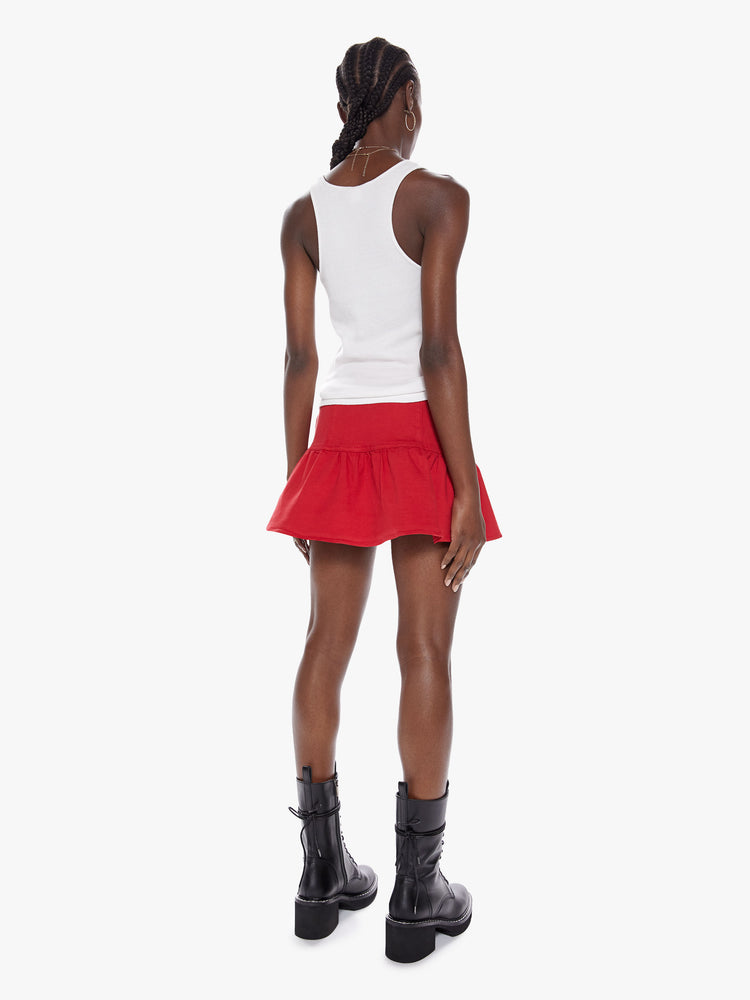 Back view view of a womens red mini high rise skirt with a snug waist, side zipper, and ruffles along the hem.