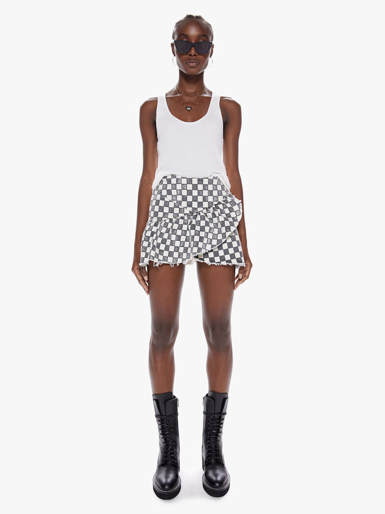 Front view of a womens black and white checkered mini high rise skirt with a snug waist, side zipper, and ruffles along the frayed hem.