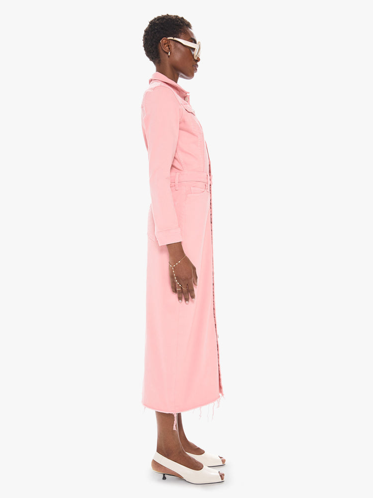 Side view of a women's light pink button down denim dress with a long sleeves and a frayed midi length hem