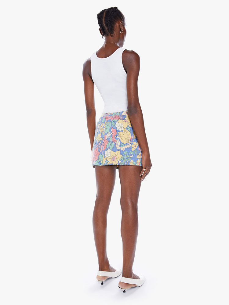 Back view of a woman denim mini skirt with a high rise, button-fly, slim fit and thigh-grazing hem in a faded floral print.