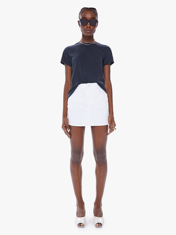 Front view of a woman denim mini skirt with a high rise, button fly, slim fit and thigh-grazing hem in white.
