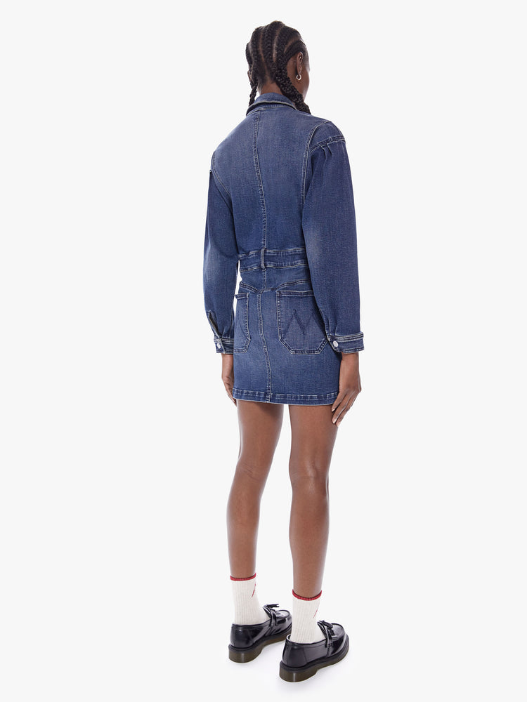 Back full body view of a woman in a collared denim mini dress with long batwing sleeves, a belted high waist and snaps down the front, cut from semi-rigid Superior denim in Beer Me that is a mid blue wash with fading, whiskering and a seamed details throughout