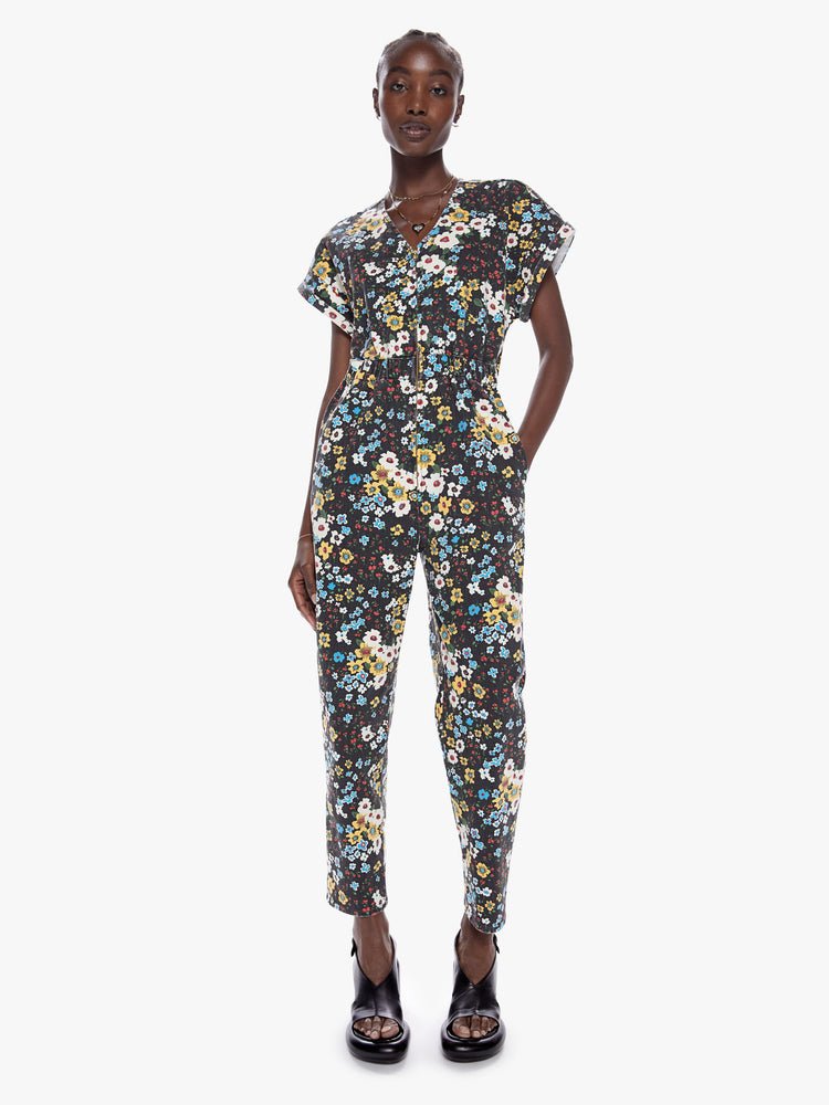 Front full body view a woman in a zip up jumpsuit featuring a vneck, rolled short sleeves, a cinched waist and a clean ankle length hem made from cotton with a touch of stretch, pushing daisies is a high contrast floral print in black, blue, yellow, red, and white