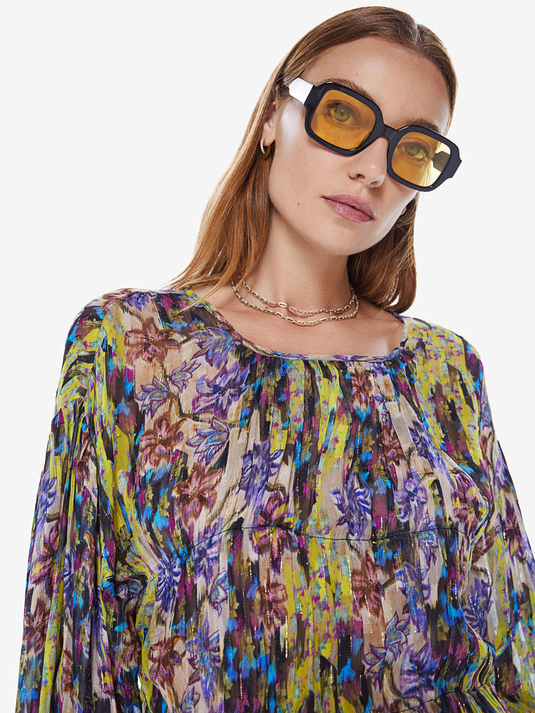 Close up view of a woman in a Maria Cher long sleeve top designed in a bright yellow and purple abstract print, the long sleeve blouse features a crewneck, balloon sleeves and a loose, flowy fit