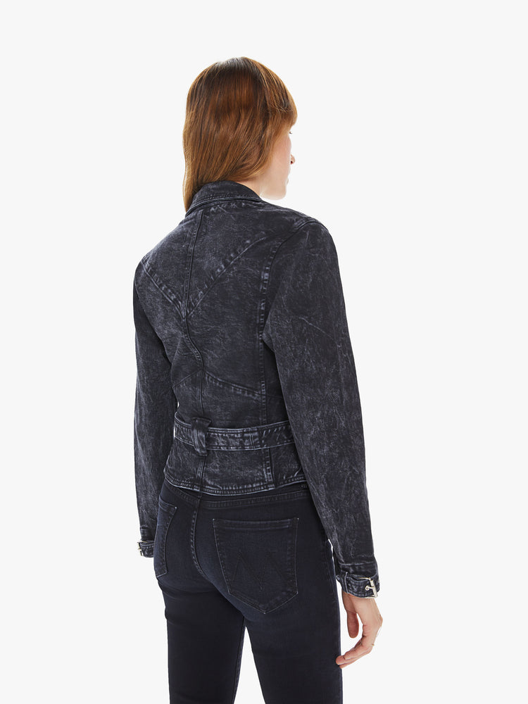 Back view of a woman wearing a washed black moto jacket featuring a fitted, cropped body and a belted waist.