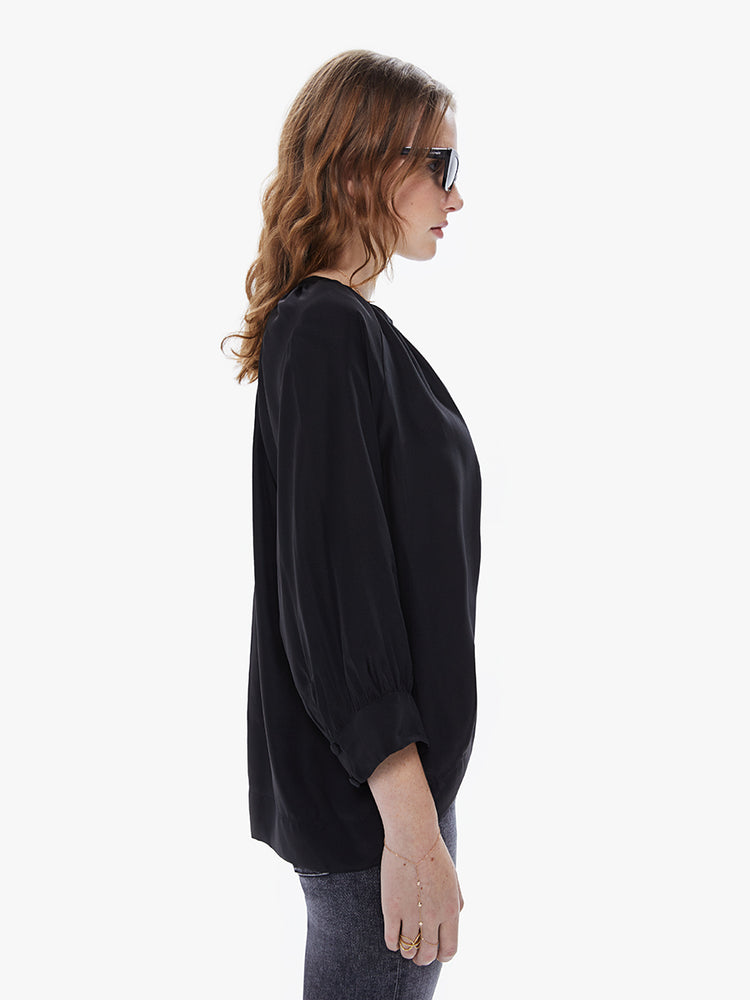 A side view of a Womens black blouse featuring a v-shaped neckline, covered buttons, and subtle pleats below the collar.