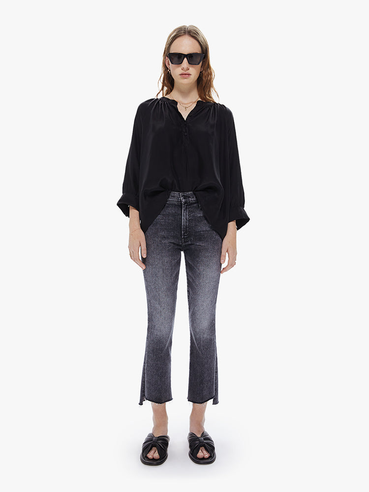 A front full body view of a Womens black blouse featuring a v-shaped neckline, covered buttons, and subtle pleats below the collar.