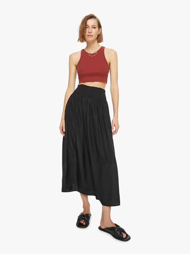Front view of a womens black mid length skirt, featuring an elastic high rise waist and flowy fit.
