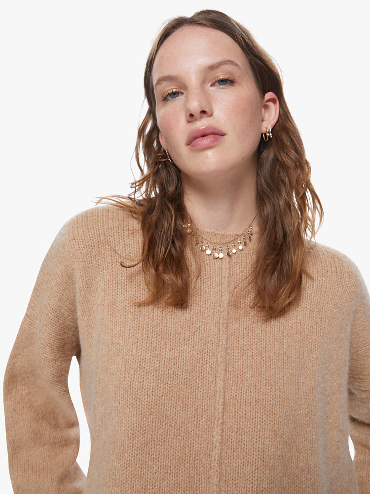 Front close up view of a women's camel brown knit sweater featuring a scoop neck, a center seam, and a loose fit.