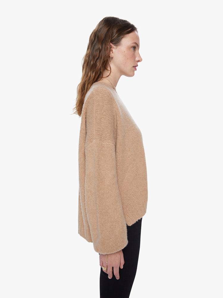 Side view of a women's camel brown knit sweater featuring a scoop neck, a center seam, balloon sleeves, and a loose fit.