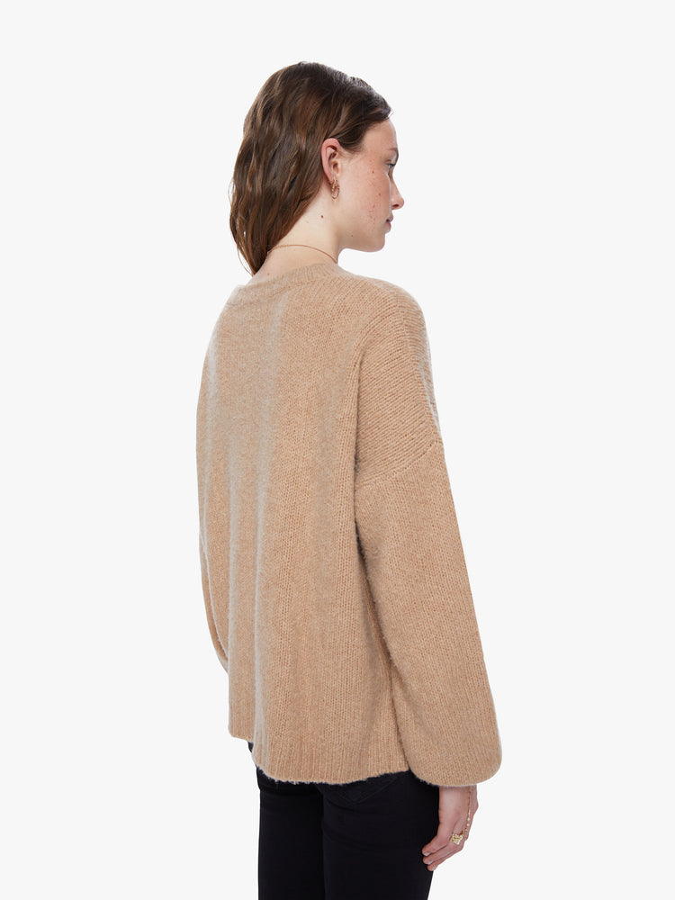 Back view of a women's camel brown knit sweater featuring a scoop neck, a center seam, balloon sleeves, and a loose fit.