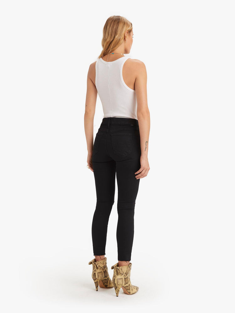 back view of women's black mid rise skinny jean with distressed knees, zip fly, ankle inseam, and frayed hem