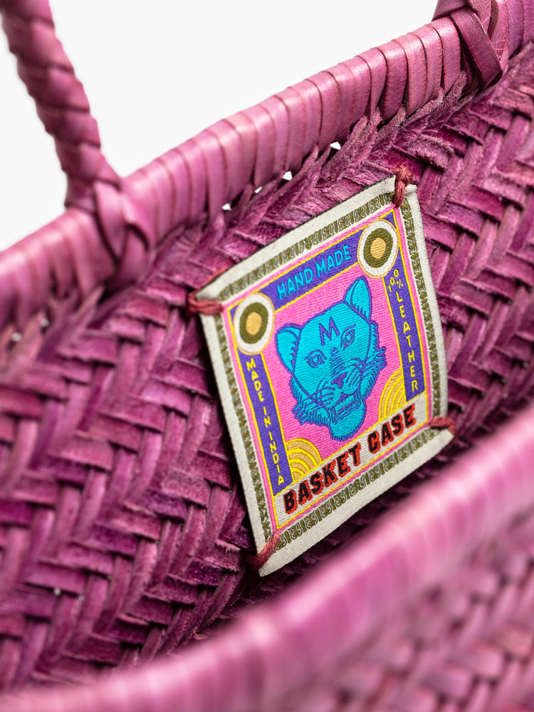 Front view of the inner label of a pink, woven leather bag.